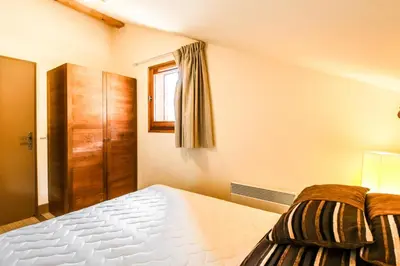 a bedroom with a bed and a wooden cabinet at Les Terrasses d'Eos, 1-bed apartment with fireplace, Ski in, Ski out in Flaine