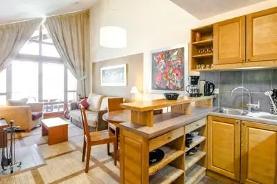 a kitchen with wooden cabinets and a living room at Les Terrasses d'Eos, 1-bed apartment with fireplace, Ski in, Ski out in Flaine