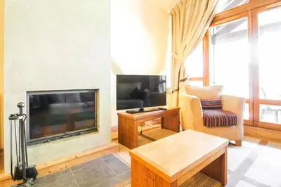 a living room with a large television and a chair at Les Terrasses d'Eos, 1-bed apartment with fireplace, Ski in, Ski out in Flaine