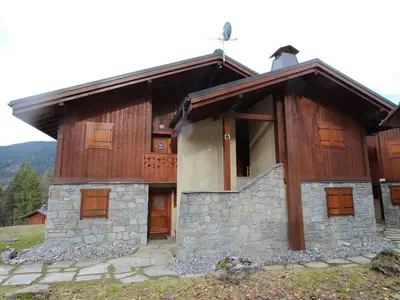 a house with wooden doors and a stone facade at Chalet 4 pièces + mezzanine, 8 pers, WiFi, parking, proche spa, arrêt ski-bus - FR-1-572-112 in Les Carroz d'Araches