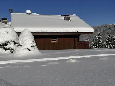 a house covered in snow with trees in the background at Chalet 4 pièces + mezzanine, 8 pers, WiFi, parking, proche spa, arrêt ski-bus - FR-1-572-112 in Les Carroz d'Araches