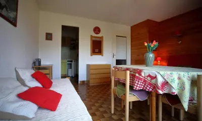 a room with a table and chairs with red pillows at PE255 Studio 4 pers pieds de piste in Les Carroz d'Araches