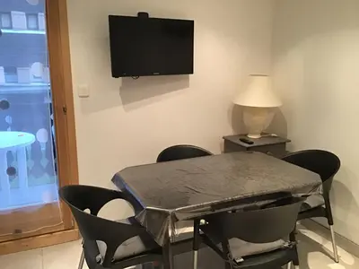 a room with a table and chairs and a tv on the wall at VAR50 - Studio 4 Pers centre des Carroz in Les Carroz d'Araches