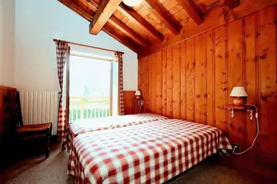a bedroom with a bed with a checkered blanket and a window at Chalet Ulysse - Chalet Ulysse MAE-6403 in Les Houches