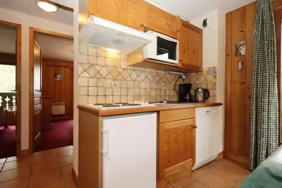 a kitchen with wooden cabinets and a white refrigerator at Résidence Le Saint Georges - Saint-Georges 07 MAE-6405 in Les Houches