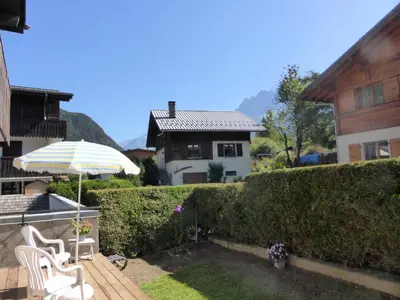 a patio with an umbrella and chairs and a house at Résidence Aiguille Du Midi Bat A - Aiguille du Midi A778 MAE-6406 in Les Houches