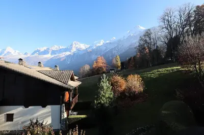 a house on a hill with mountains in the background at Résidence Les Hauts De Chavants - Hauts de Chavants Berard 10 MAE-6415 in Les Houches