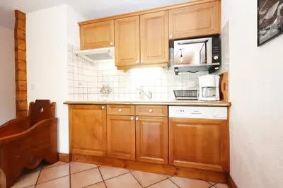 a kitchen with wooden cabinets and a microwave at Résidence Les Hauts De Chavants - Hauts de Chavants Berard 04 MAE-6426 in Les Houches