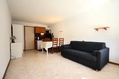 a living room with a black couch and a kitchen at Résidence Le Prarion 2 C - Prarion 2 C13 MAE-6430 in Les Houches
