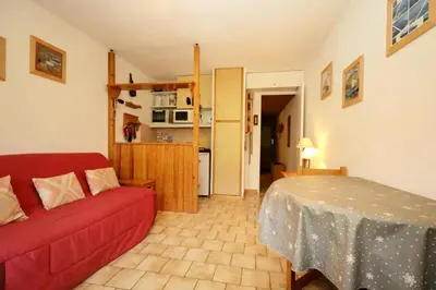a living room with a red couch and a kitchen at Résidence Le ChÂteau Bruyeres - Château B42 MAE-6432 in Les Houches