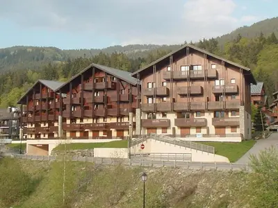 a large building with a tennis court in front of it at Appartement Central 6 Pers, Parking, Ascenseur, Proche Pistes et Commerces - FR-1-572-22 in Les Carroz d'Araches