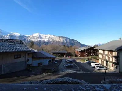 a parking lot with buildings and a mountain in the background at Appartement 8 pers, 4 pièces, 50m des pistes, parking, balcon, proche commerces - FR-1-572-88 in Les Carroz d'Araches