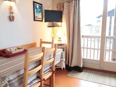 a bedroom with a bed and a balcony with a television at Studio chaleureux 4 pers, centre village, proche pistes et commerces, balcon sud-ouest - FR-1-572-105 in Les Carroz d'Araches