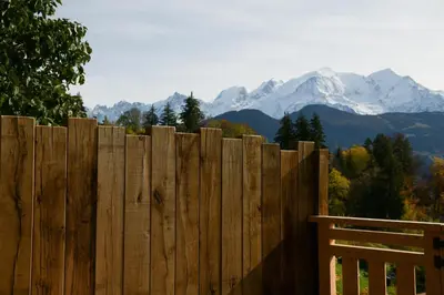 a wooden fence with snow capped mountains in the background at Le Mazot d'la Marmotte Studio in Passy