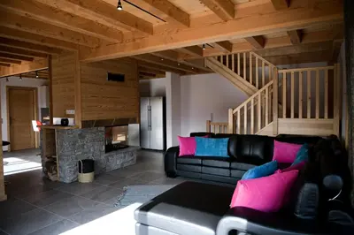 a living room with a black leather couch and a fireplace at Le Mazot d'la Marmotte T3 in Passy