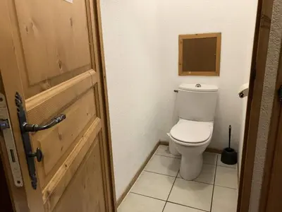 a bathroom with a toilet and a wooden door at Résidence Le Grand Panorama - Grand Panorama 001 MAE-5280 in Saint-Gervais-les-Bains