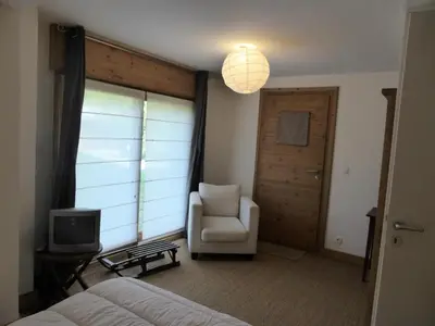a bedroom with a bed and a chair and a television at Chalet Champelet - Chalet Champelet MAE-5333 in Les Contamines-Montjoie
