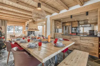 a dining room and kitchen with a wooden table and chairs at Chalet Nepal in Megève