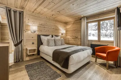 a bedroom with a bed and a chair and a window at Chalet Nepal in Megève