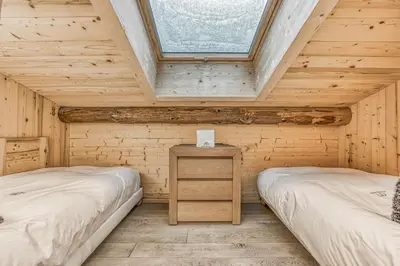 two beds in a wooden room with a window at Chalet Nepal in Megève