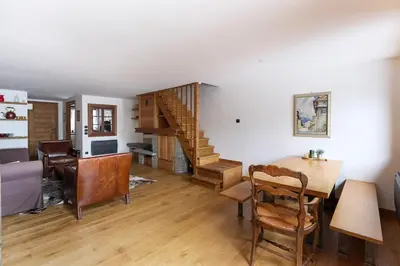 a living room with a wooden table and a staircase at House Berenice - Chamonix les Praz in Chamonix-Mont-Blanc