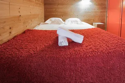 a bed with a red blanket and white towels on it at House Berenice - Chamonix les Praz in Chamonix-Mont-Blanc