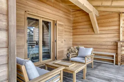 a cabin with a porch with two chairs and a table at Appartement Amour in Megève