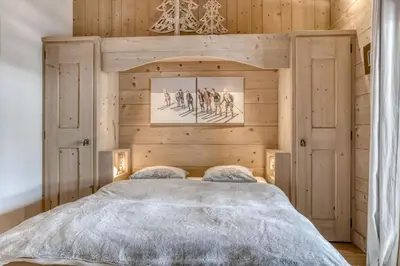 a bedroom with a bed with a wooden wall at Appartement Amour in Megève
