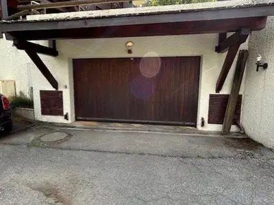 a garage with a brown door on the side of a building at Appartement 3 pièces+cabine à Megève, près des pistes, terrasse, parking, 6 couchages - FR-1-597-1 in Megève