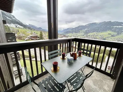 a table and chairs on a balcony with mountains at Appart 2 pièces + mezzanine, 6 couchages, Megève, parking - FR-1-597-7 in Megève