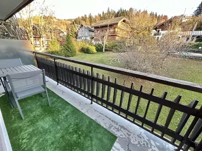 a balcony with green grass and a table and a fence at Studios + Cabine à Megève, 4 Couchages, 500m des Remontées, Balcon Sud, Parking Inclus - FR-1-597-34 in Megève