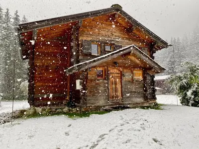 a wooden cabin in the snow with snow falling at Chalet Orval - Chamonix Argentière in Chamonix-Mont-Blanc