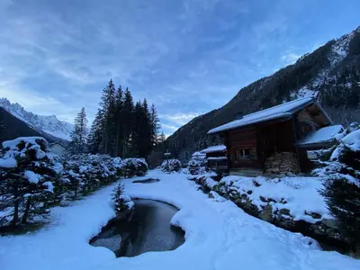 a cabin in the snow next to a stream at Chalet Orval - Chamonix Argentière in Chamonix-Mont-Blanc