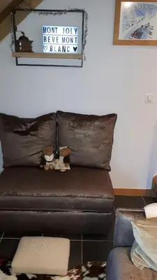 a brown leather couch with stuffed animals on top of it at Duplex 6 pers, garage, WIFI, calme, proche des pistes, vue magnifique in Saint-Gervais-les-Bains