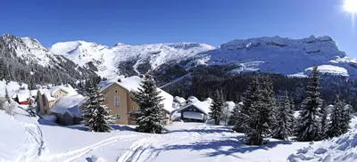 a house in the snow with a mountain in the background at Résidence Hameau - Chalet lumineux · Poêle à bois · Sauna · Garage MAE-7348 in Flaine