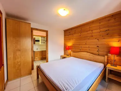 a bedroom with a bed and a wooden wall at Résidence Hameau - Chalet lumineux · Poêle à bois · Sauna · Garage MAE-7348 in Flaine
