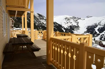 a wooden porch with a table and snow covered mountains at Résidence Hameau - Chalet spacieux · Sauna · Cheminée MAE-7349 in Flaine