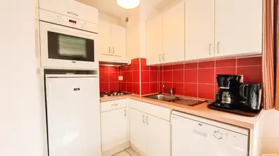 a small kitchen with white cabinets and red tiles at Résidence Les Pleiades - Appartement lumineux et confortable · Centre station · Balcon · Parking couvert MAE-7351 in Flaine