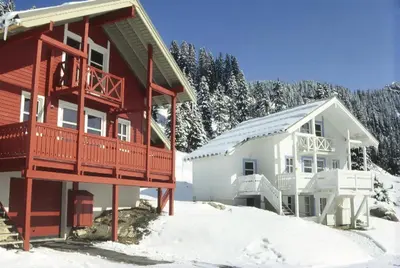 a home in the snow next to a building at Résidence Hameau - Chalet lumineux · Poêle à bois · WIFI gratuit et illimité · Garage MAE-7353 in Flaine