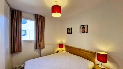 a bedroom with a bed with two lamps and a window at Résidence Les Pleiades - Appartement spacieux et lumineux · Centre station · Balcon · Parking couvert MAE-7354 in Flaine