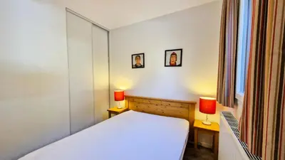 a bedroom with a white bed and two lamps at Résidence Les Pleiades - Appartement spacieux · Centre station · Balcon · Parking couvert MAE-7356 in Flaine