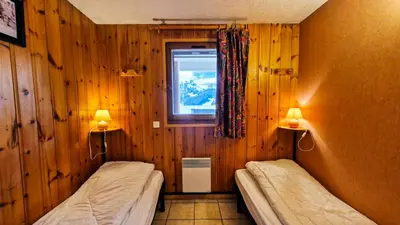 two beds in a room with wooden walls and a window at Résidence Arche - Appartement spacieux · Centre station · Balcon MAE-7358 in Flaine