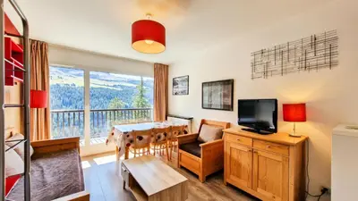 a living room with a dining room table and a television at Résidence Les Pleiades - Appartement confortable avec cabine · Centre station · Balcon · Parking couvert MAE-7366 in Flaine
