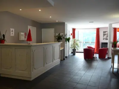a hotel lobby with a reception counter and red chairs at Résidence Les Pleiades - Appartement lumineux · Centre station · Balcon · Parking couvert MAE-7373 in Flaine