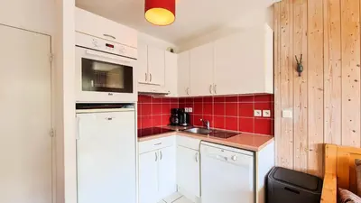 a small kitchen with white cabinets and red tiles at Résidence Les Pleiades - Appartement lumineux · Centre station · Balcon · Parking couvert MAE-7373 in Flaine