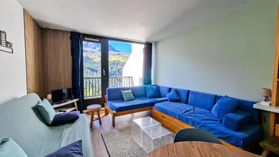 a living room with a blue couch and a large window at Résidence Belier - Appartement confortable · Au pied des pistes · WIFI gratuit et illimité · Terrasse MAE-7374 in Flaine