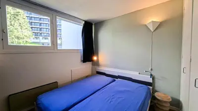 a bedroom with a blue bed and two windows at Résidence Belier - Appartement confortable · Au pied des pistes · WIFI gratuit et illimité · Terrasse MAE-7374 in Flaine