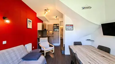 a living room with a table and a red wall at Résidence Les Terrasses De Veret - Appartement confortable · Au pied des pistes · Piscine · Spa · Parking MAE-7377 in Flaine
