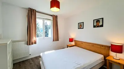 a bedroom with a bed and two lamps and a window at Résidence Les Pleiades - Appartement spacieux · Centre station · Parking couvert · Balcon MAE-7381 in Flaine