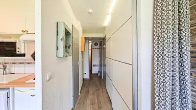 a hallway leading into a kitchen with white walls and wooden floors at Résidence Sagittaire - Studio entièrement rénové avec cabine · Centre station · Balcon MAE-7390 in Flaine